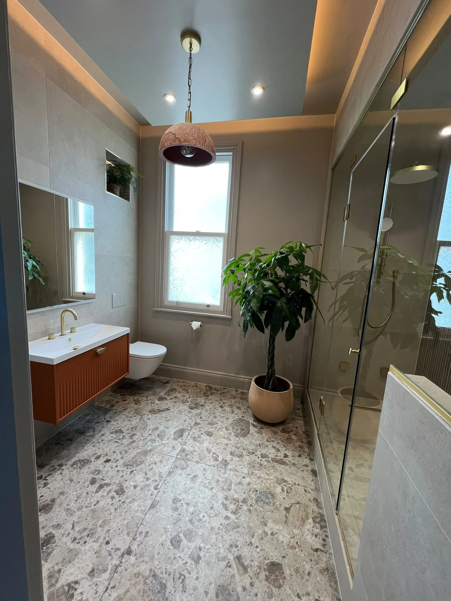 Full Bathroom View With An Orange Vanity, Glass-Screened Shower And Illuminated Patterned-Tile Arch.
