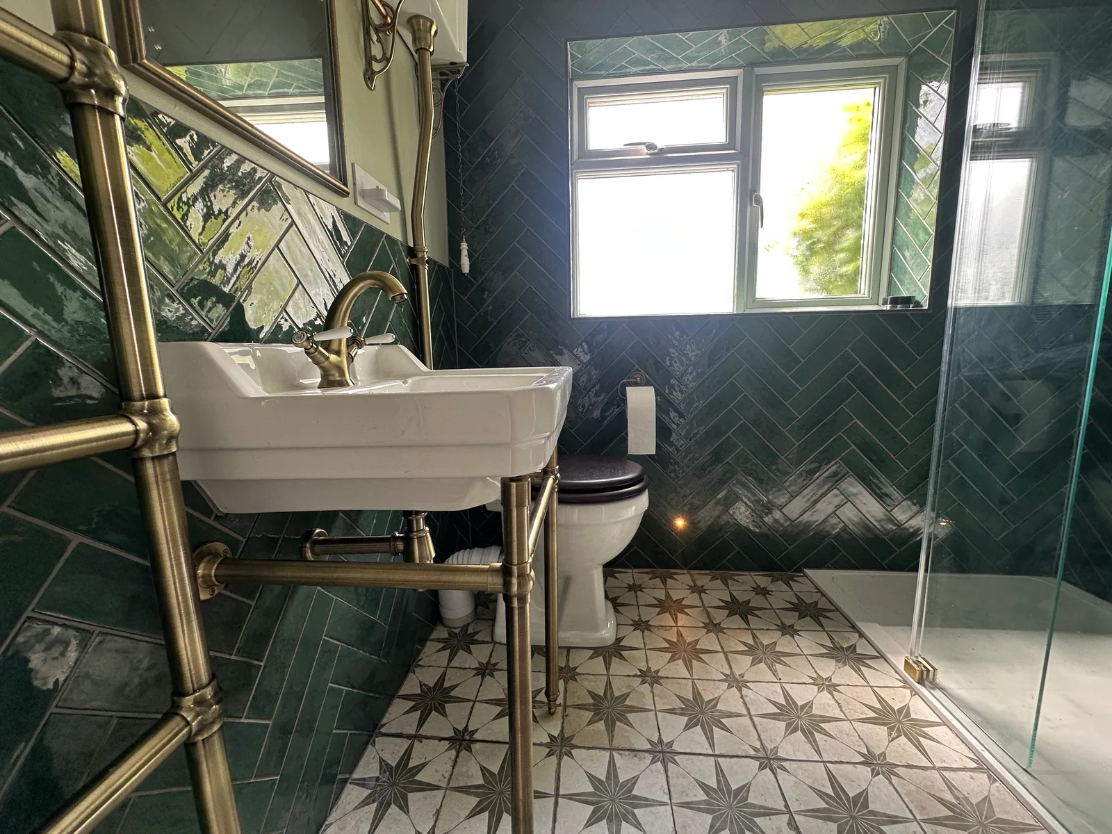 Finished shower room in Bishops Cleeve with teal herringbone tiles, patterned floor and traditional-style fittings.