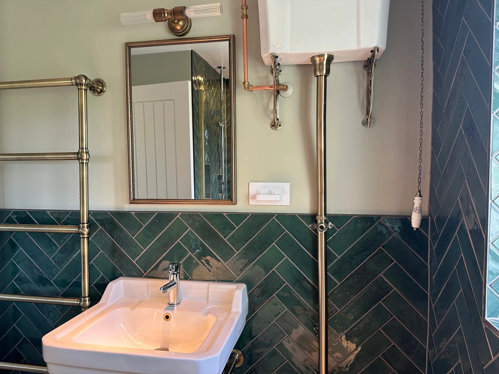 Traditional-style basin and mirror beneath a high-level cistern in the Bishops Cleeve shower room.