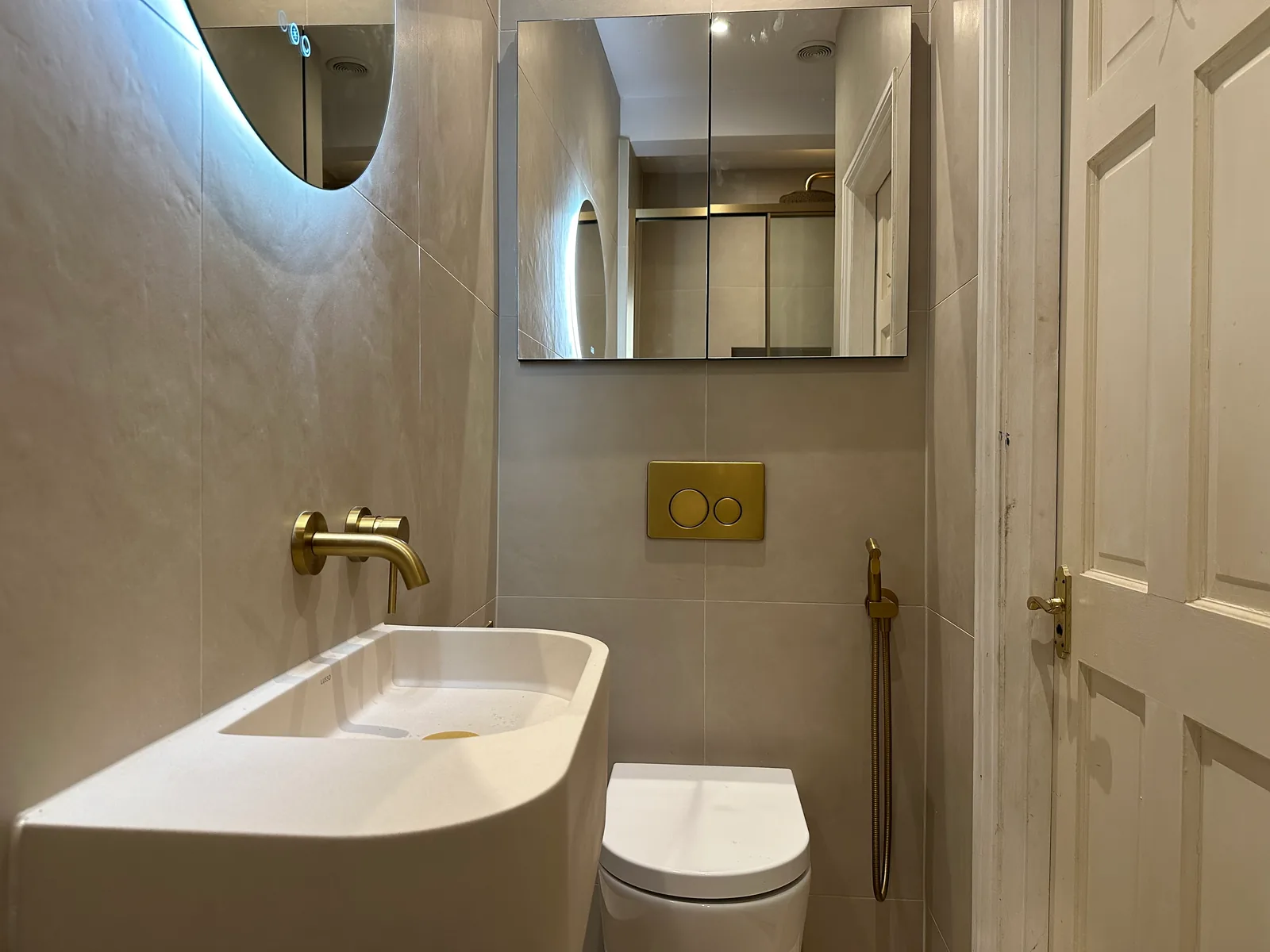 Compact Cheltenham shower-room layout with a wall-mounted basin, wall-hung toilet and mirrored storage.